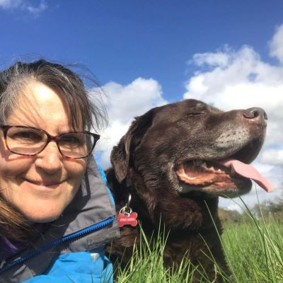 Sarah and a chocolate lab laying on the grass on a summers day.